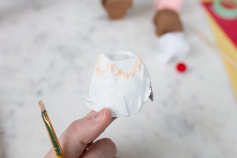 Cut one egg cup out of the carton. Flip upside down and paint it white (or any frosting color you’d like). Let it dry completely. In a complementary paint color, decorate with paint. Let it dry completely. 