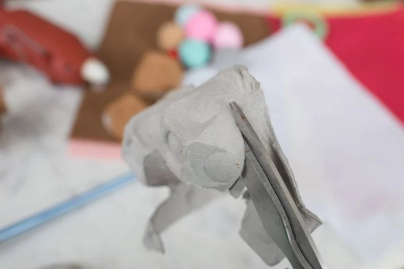 Start by cutting down the egg cup part of the carton down, so you’re left with only the circular domed tops. 