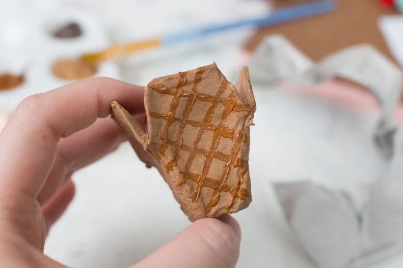 Paint it a light tan and let it dry completely. With a thinner brush, paint lines going diagonally across the cone surface. Paint crisscrossing lines to form the waffle cone patterns. 