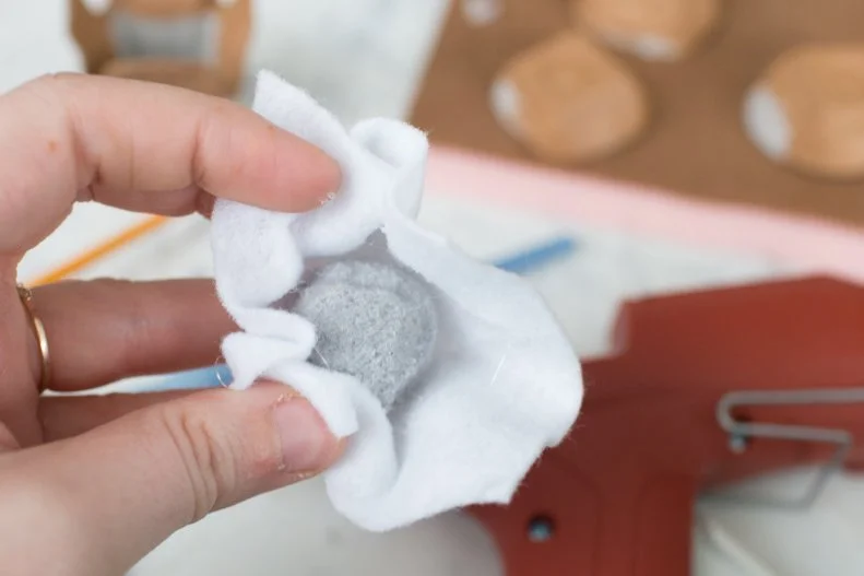 Take a large pom-pom and glue ice cream colored felt around it to create a scoop of ice cream. Repeat with different colors — simulating favorite flavors — until you have enough “scoops” to fill the cone. 