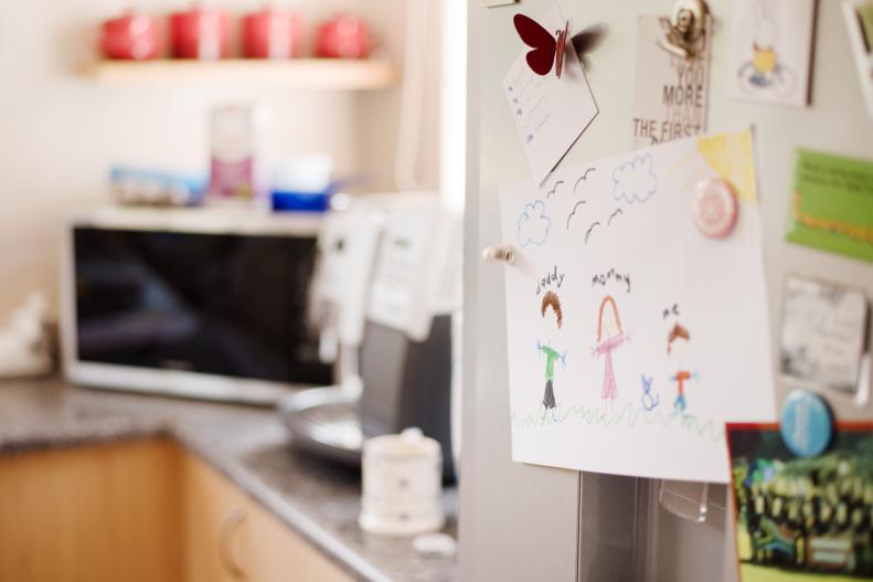Colorful kid's drawings and pictures decorated on kitchen refrigerator door