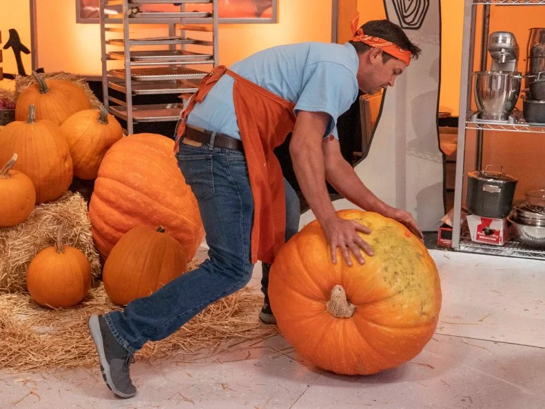 Team Candy Coroners Pumpkin Carver Chad Gaine rolls a giant pumpkin toward his station during Episode 3 Spine Chiller challenge "Monster Support Group" as seen on Halloween Wars, Season 10.