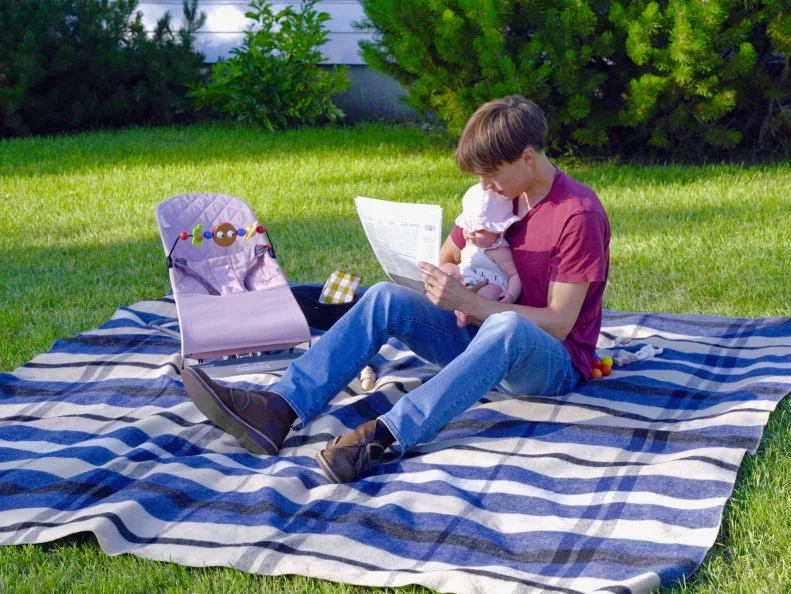 Molly's husband, Nick, plays with their daughter while Molly finishes prepping the food ,as seen on Girl Meets Farm, Season 4.