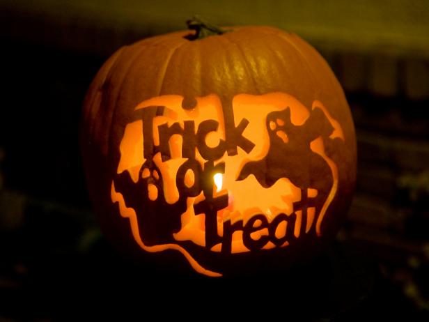 A pumpkin carving in the shape of ghosts and the words "Trick or Treat"