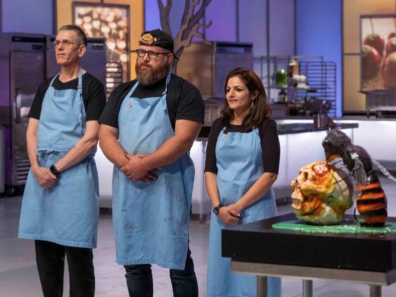 Left to Right: Team Mummies Rejects Sugar Expert Steve Weiss, Pumpkin Carver Daniel Miller and Cake Maker Helmata Basumatary face the judges with their creation during Episode 5 Small Scare challenge "Giant Bugs Attack!" as seen on Halloween Wars, Season 10.