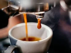 Fresh espresso shot pouring out of machine.