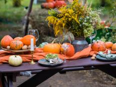 Fall themed holiday table setting arrangement for a seasonal party, glasses, pumpkins, candles, field flowers