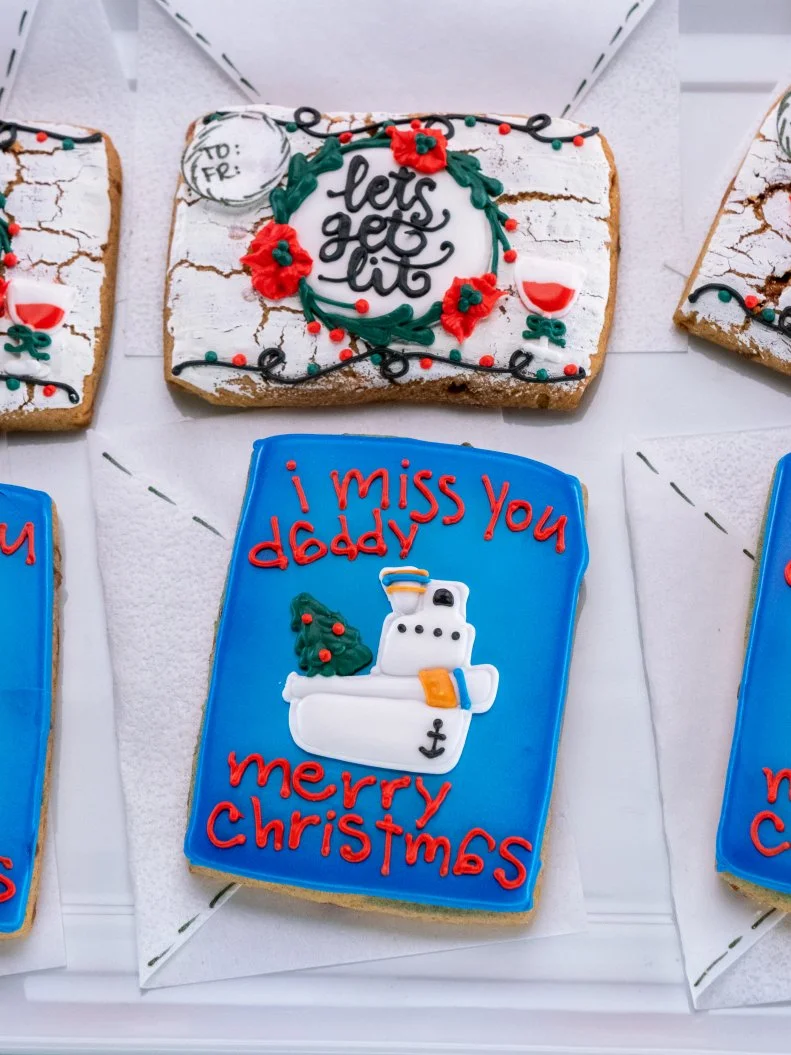Contestant Stephanie Bruce-Torres' dish is flavor: pumpkin spice toffee cookie with vanilla royal icing, sincere: blue card that reads "I miss you daddy...Merry Christmas" with a boat and tree on it, funny: white card with lights and a wine glass that reads "Let's get lit",   during the first challenge, as seen on Christmas Cookie Challenge, Season 3.