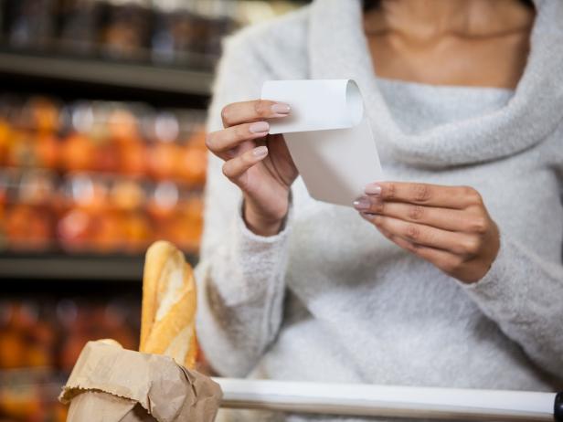 Mid section of woman holding bill in grocery section of supermarket