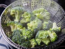 Freshly steamed green broccoli in skimmer pot with steam