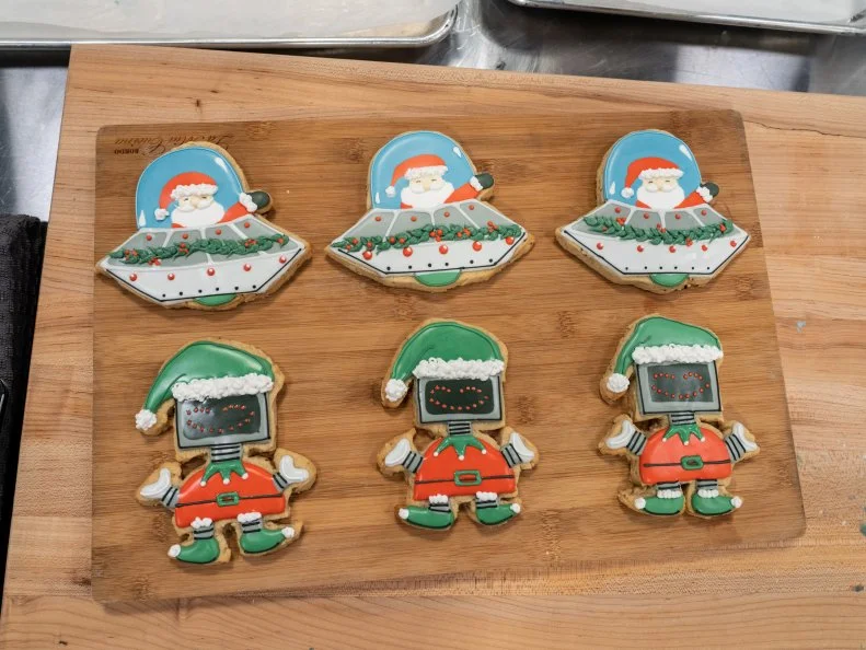 Contestant Ashlee's Cinnamon almond vanilla cookies with vanilla royal icing with Santa in a flying saucer and Robot Eld design, as seen on Christmas Cookie Challenge, Season 4.