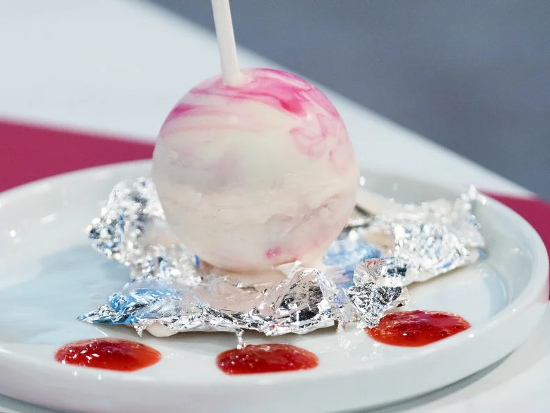 Mini Treat created by Ray Miranda-Vizcaino which is a strawberry mousse cheesecake with strawberry coulis & streusel inside a marbled chocolate sphere styled to look like a "chupa chupa" lollipop. The foil is an "edible wrapper" to really sell the "lollipop" feature... but there is  a total surprise inside, as seen on Candyland, Season 1.