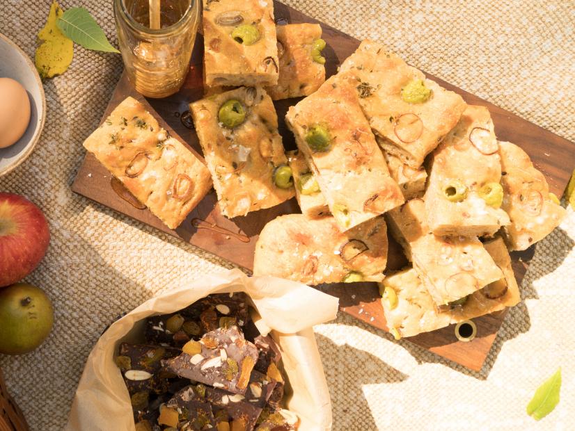 Host Sarah Copeland's picnic spread, including her Homemade Green Olive, Shallot and Rosemary Focaccia Bread and Apricot, Golden Raisin and Smoked Almond Chocolate Bark, as seen on Every Day is Saturday, Season 2.