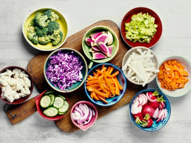 Chopped vegetables in colorful bowls on white background