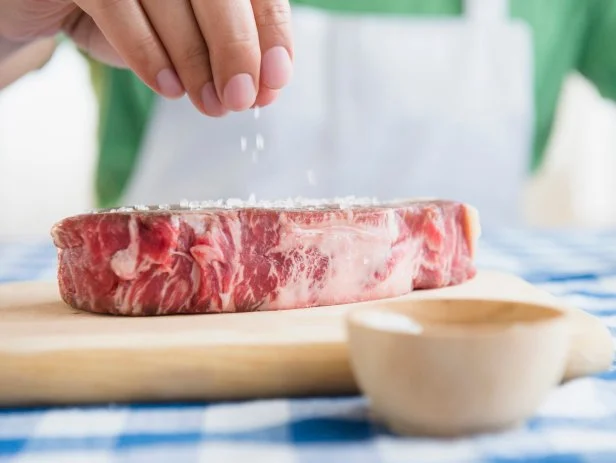Close up of mixed race man sprinkling salt on steak