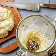 Raw Cauliflower ground in food processor for making Cauliflower Rice on concrete background