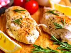 Chicken breast baked with rosemary on a cuuting board.
