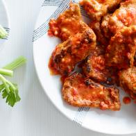 Vegan Seitan Wings on plate with celery and dipping sauce on white table