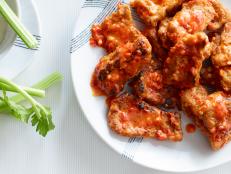 Vegan Seitan Wings on plate with celery and dipping sauce on white table