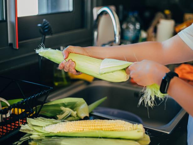 Woman shucking the corn before cooking in the kitchen