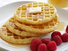 Breakfast plate of waffles and raspberries, butter and maple syrup