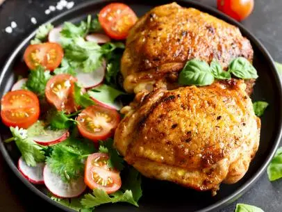 Fried chicken thighs with vegetables in plate