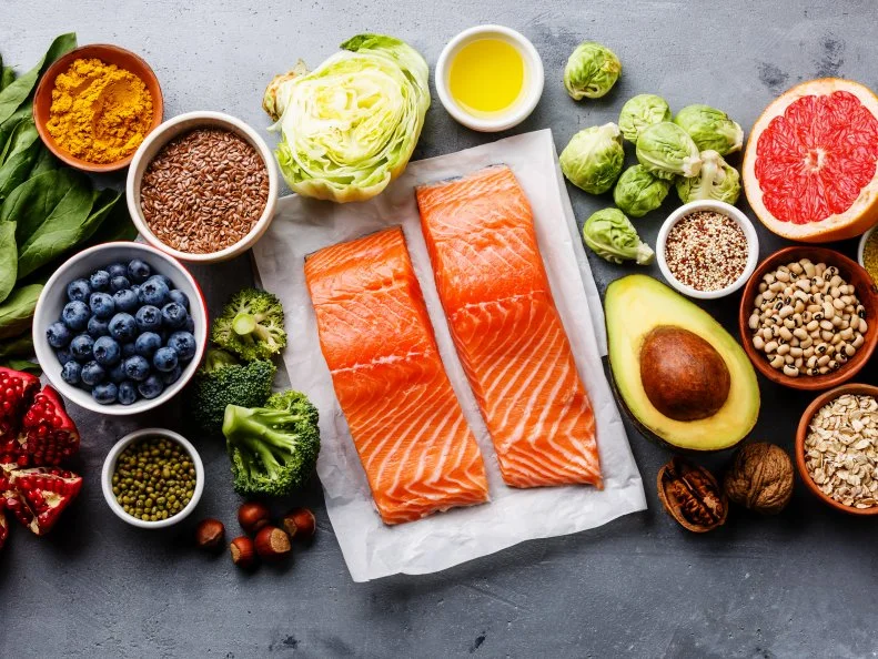 Healthy food clean eating selection: fish, fruit, vegetable, seeds, superfood, cereals, leaf vegetable on gray concrete background copy space