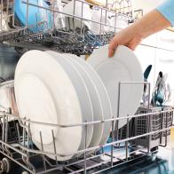 close-up of female hands loading dishes to the dishwasher