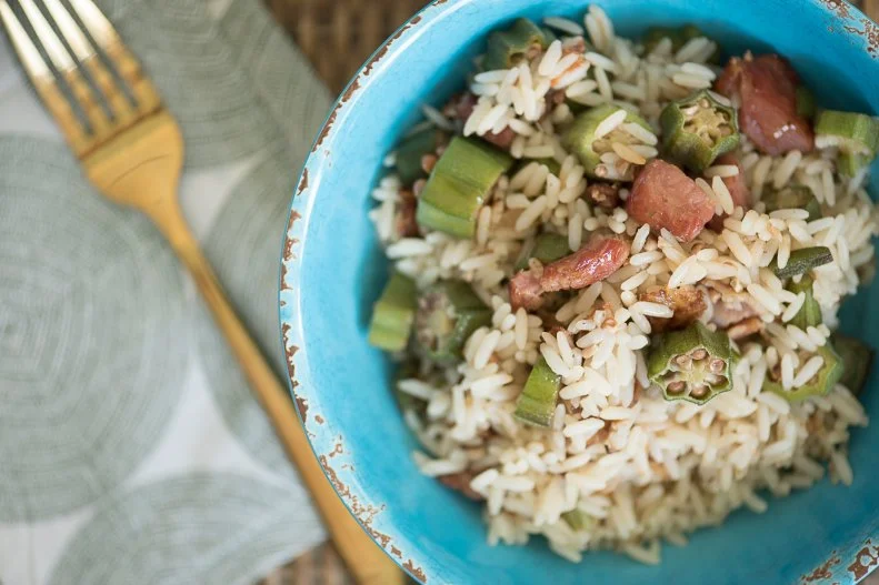 Okra Pilau plated in blue bowl with golden fork, as seen on The Juneteenth Menu
