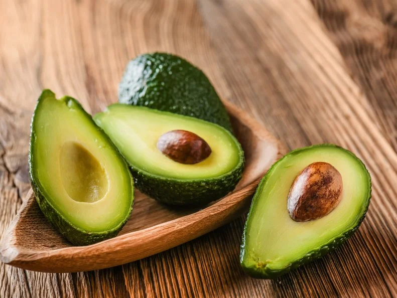Avocado on old wooden table in bowl. Halfs of avocados fresh fruits healthy food.