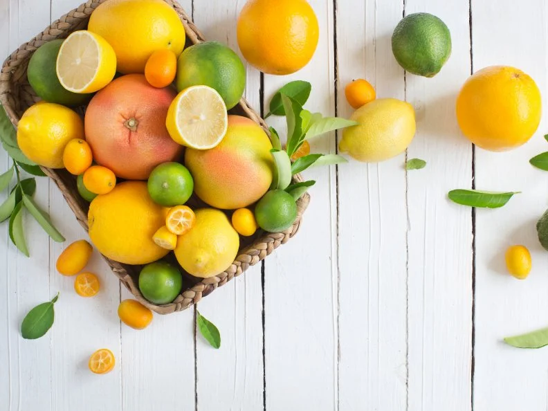 Citrus fruits family in basket on rustic white wooden background. Horizontal view. Text space images.