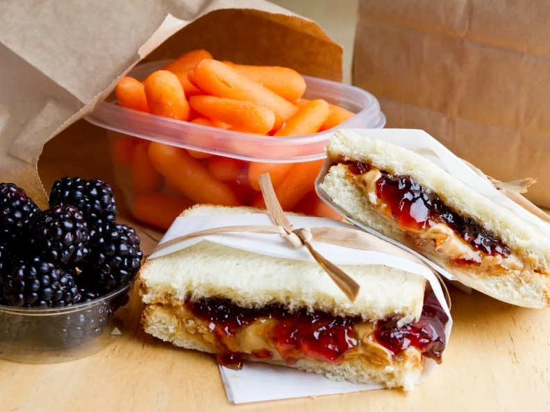 Peanut Butter and Jelly sandwich with blackberries and carrots.  Brown bag lunch.