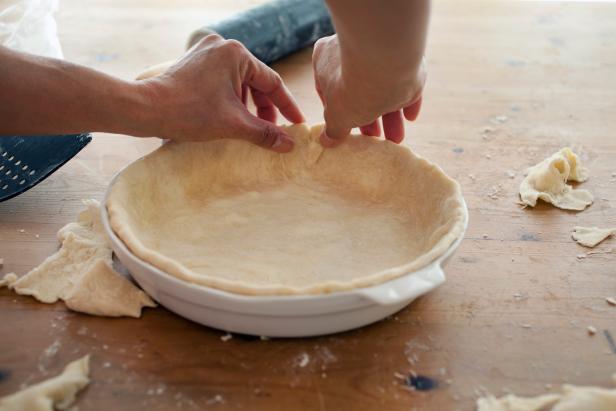 Fitting the home made pie crust into the baking dish and crimping the edges