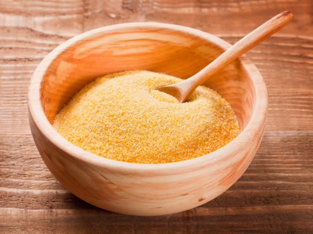 Corn grits in wooden  dish with wooden spoon on the wooden rustic table; Adobe RGB color space; see other similar images: