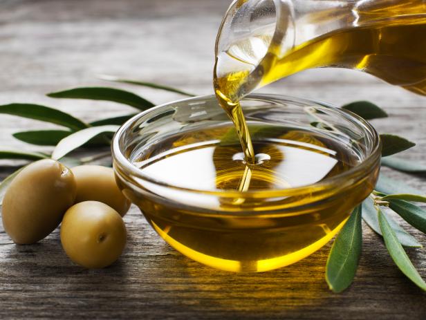 Bottle pouring virgin olive oil in a bowl close up