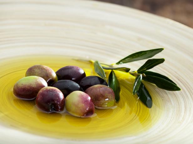 Raw olive and olive oil in wood plate.