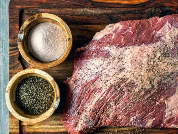 Seasoning a beef brisket with salt and pepper before barbequing on a smoker