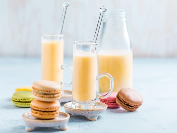 Assorted delicious French macarons with egg liqueur or eggnog on blue background