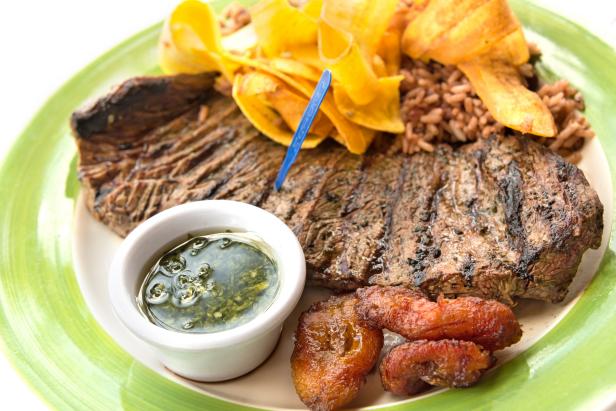 "Grilled steak with fried plantain,rice,beans and chimichurri sauce"