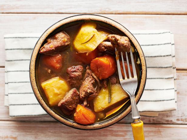 Hearty veal stew with carrots and potatoes on white wood table
