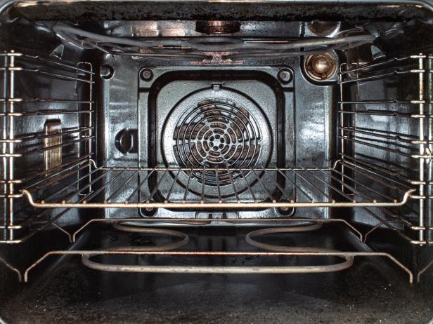 Inside view of a used open dirty stained oven and grilled metal tray 2020