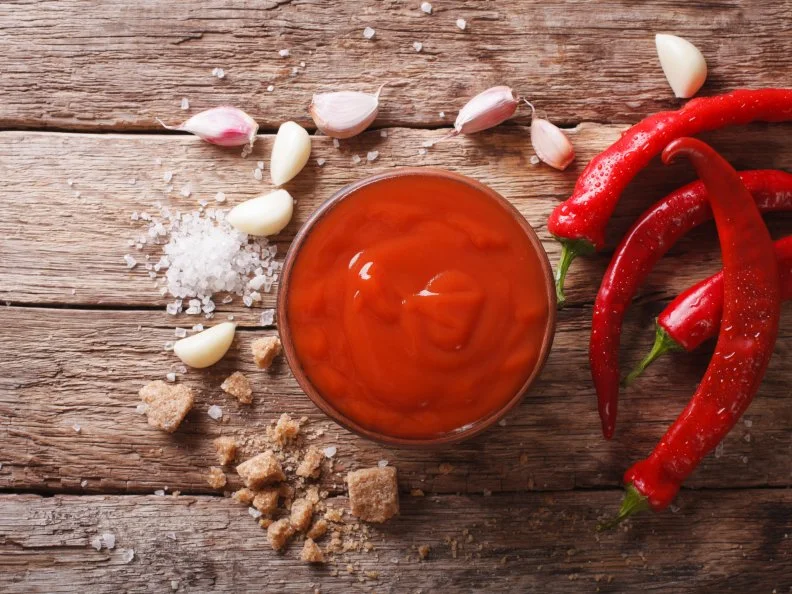 Red chilli sauce Sriracha with ingredients on the table. Horizontal view from above
