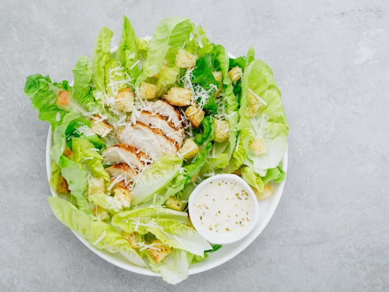 Traditional Caesar salad with chicken, romaine lettuce, croutons and parmesan cheese. Top view, copy space.