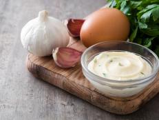 Aioli sauce and ingredients on wooden background