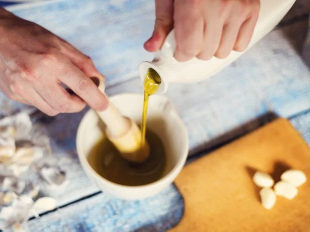 Man in the kitchen preparing a dressing with olive oil