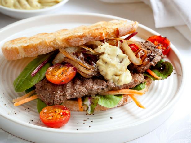 Steak sandwich with salad, grilled onions and aioli.