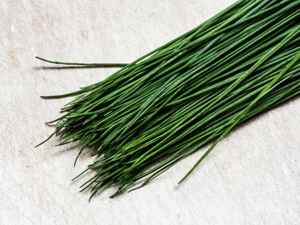 High angle close up of a bunch of fresh chives on white background.