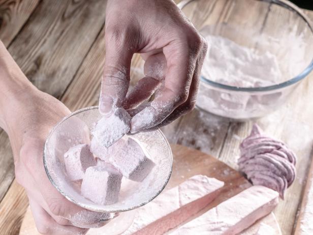Women's hands prepare delicious dessert from strawberry marshmallows