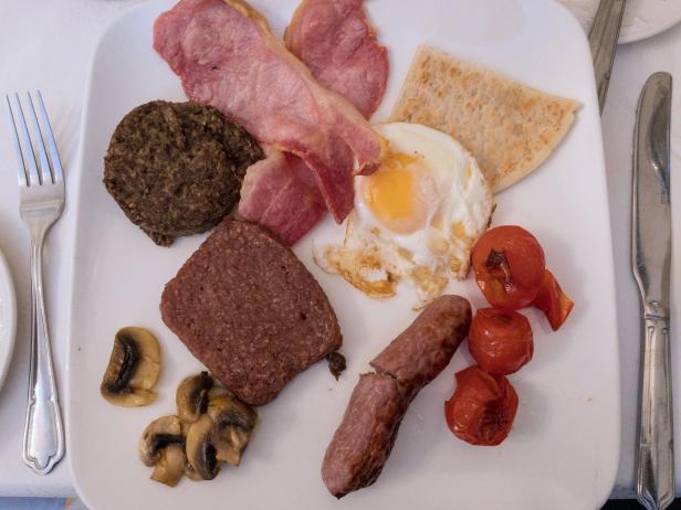 Fried egg, Ayrshire bacon, sausage link, sausage meat, haggis, mushrooms, tattie (potato) scone, mushrooms and tomatoes make up a typical traditional Scottish cooked breakfast.