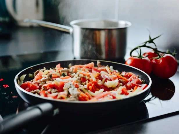Frying minced pork with vegetables on olive oil. Frying pan on induction cooker. Preparing spaghetti bolognese sauce for dinner